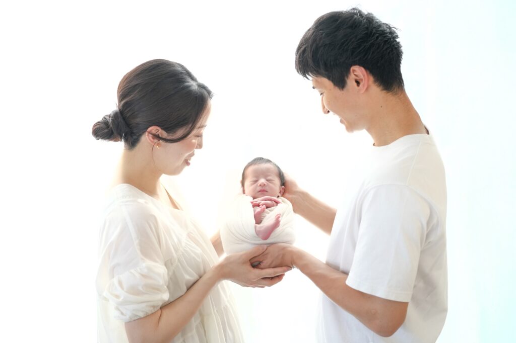 飯田市のニューボーンフォト出張撮影|赤ちゃんをパパとママがやさしく持ち上げている写真
