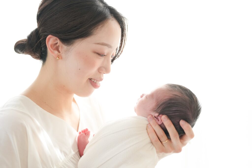 飯田市のニューボーンフォト出張撮影|ママが白い服で赤ちゃんを優しく抱っこしている写真