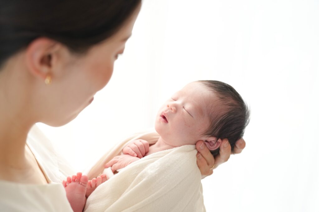 飯田市のニューボーンフォト出張撮影|パパとママの手が赤ちゃんの足を包み込んでいる写真