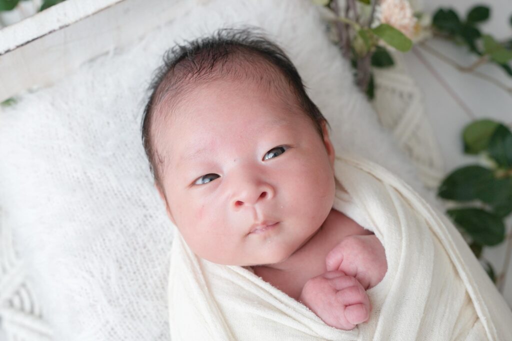 安曇野市でのニューボーンフォト|白いおくるみを巻いてカメラ目線の赤ちゃんの写真