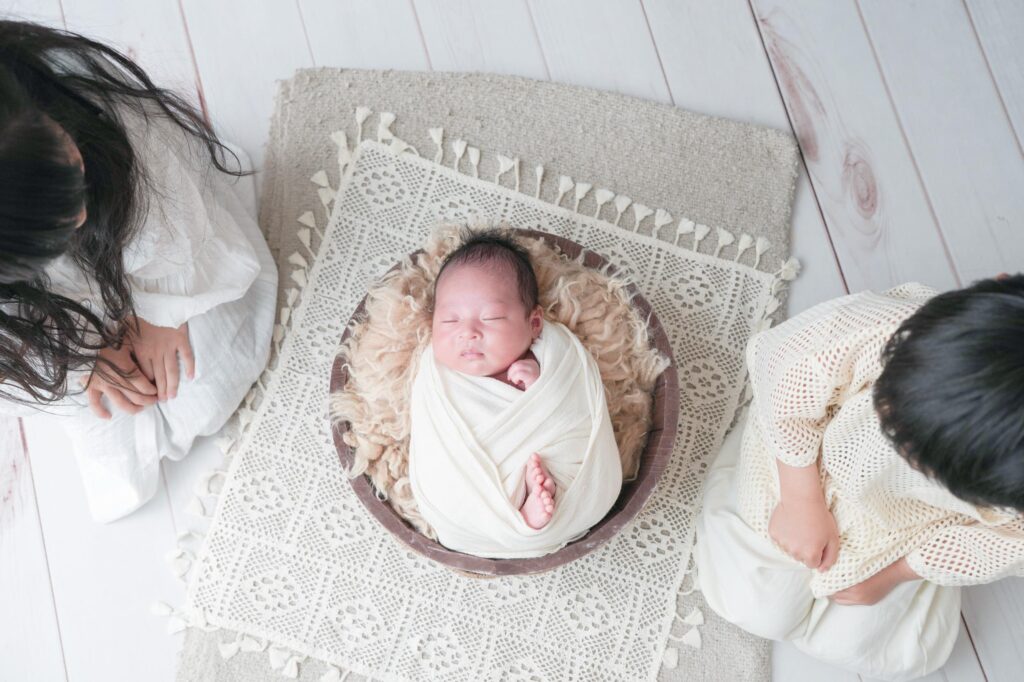 安曇野市でのニューボーンフォト|お兄ちゃんとお姉ちゃんが赤ちゃんを見つめているの写真