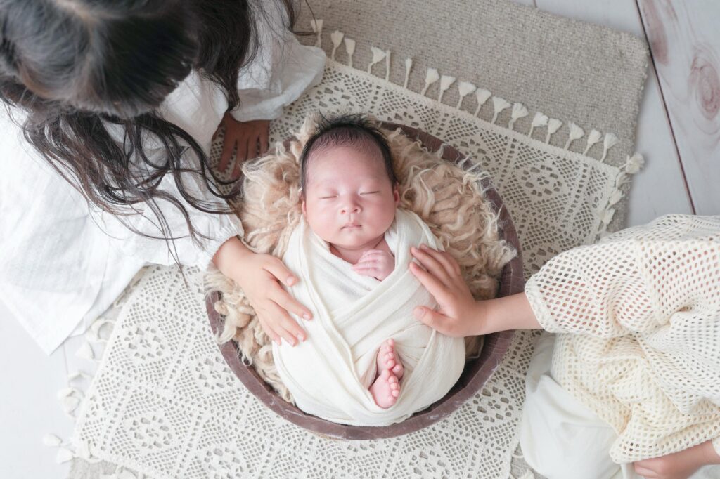 安曇野市でのニューボーンフォト|お兄ちゃんとお姉ちゃんが赤ちゃんに手を添えているの写真