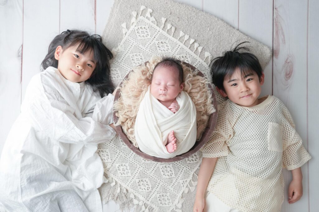 安曇野市でのニューボーンフォト|横に寝転んで赤ちゃんと一緒に写るお兄ちゃんとお姉ちゃんの写真