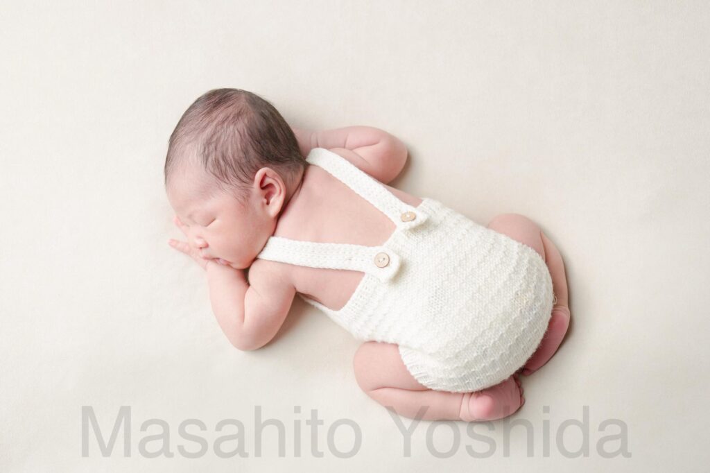 下伊那郡松川町のニューボーンフォト出張撮影|白い背景、白い服を着てうつぶせで寝ている赤ちゃんの背中の写真