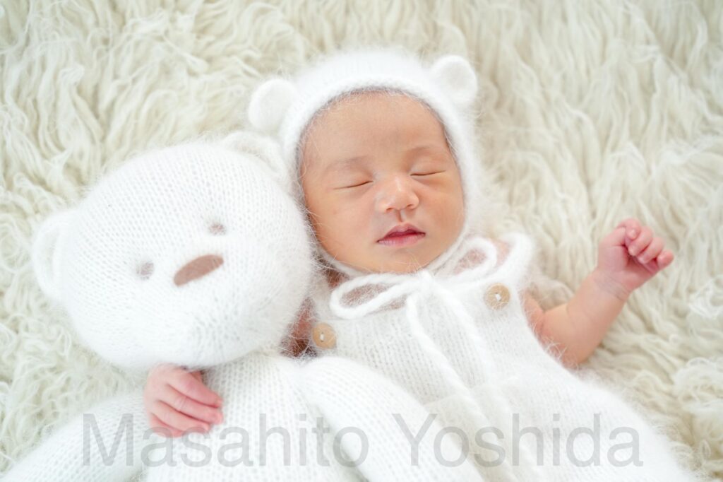 上伊那郡南箕輪村でニューボーンフォト|フロカティの上でくまのロンパースを着て、くまのぬいぐるみを抱く赤ちゃん。